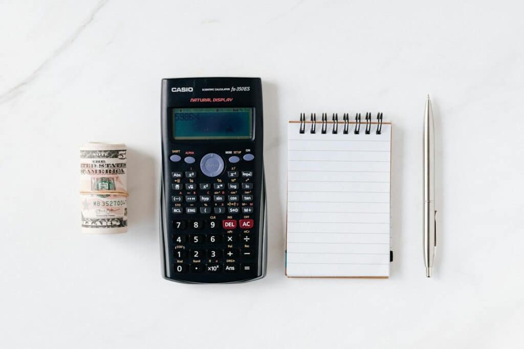 What is Net Profit? Essential Guide to Understanding and Calculation 6 Top view of financial tools including a calculator, notepad, pen, and rolled cash on a white background.