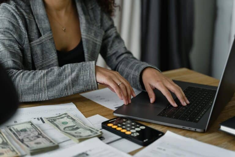 A businesswoman working on finance management with cash and calculator on desk. what is net profit